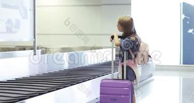 一个可爱的小女孩从<strong>行李托运</strong>箱里拿出一个紫色的手提箱。